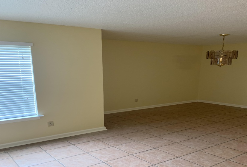 Spare room with a chandelier, a textured ceiling, and light tile patterned floors