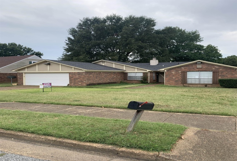 Single story home featuring brick siding, a shingled roof, a front yard, and a garage