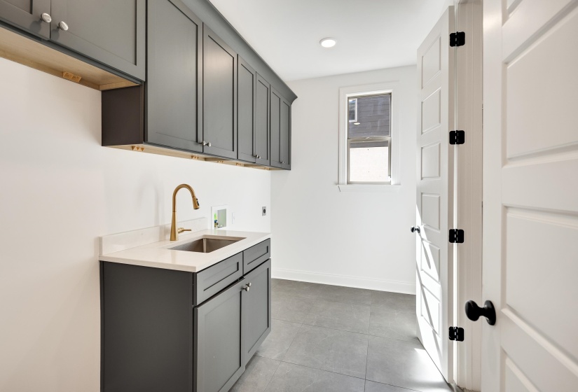 Large laundry room with extra storage, sink and room for an extra refrigerator.
