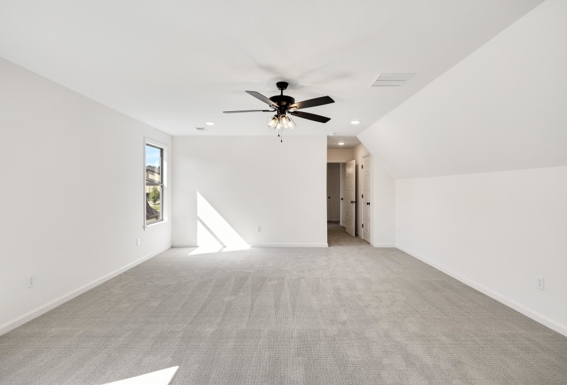 Another view of the 5th bedroom with carpet, ceiling fan and walk in closet.