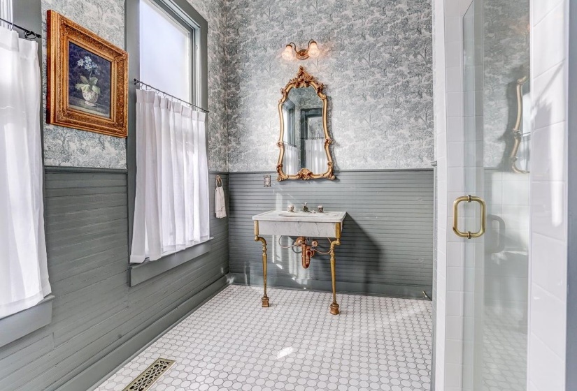 Bathroom featuring wallpapered walls, wainscoting, and a stall shower