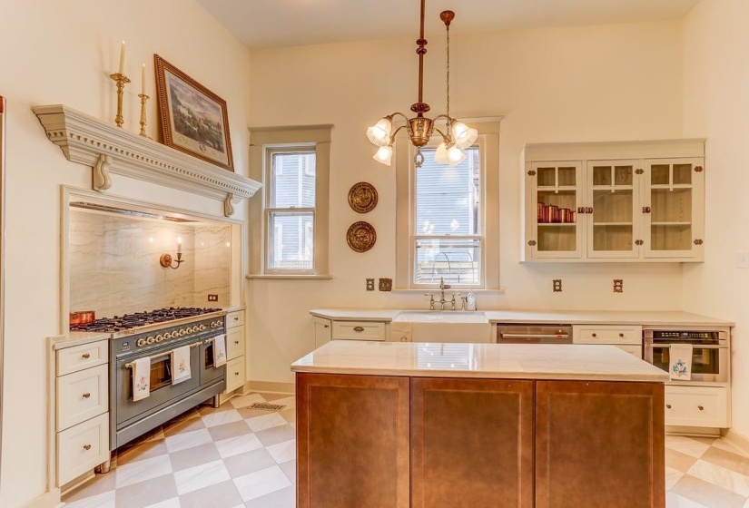 Kitchen featuring glass insert cabinets, appliances with stainless steel finishes, a kitchen island, decorative light fixtures, and a chandelier