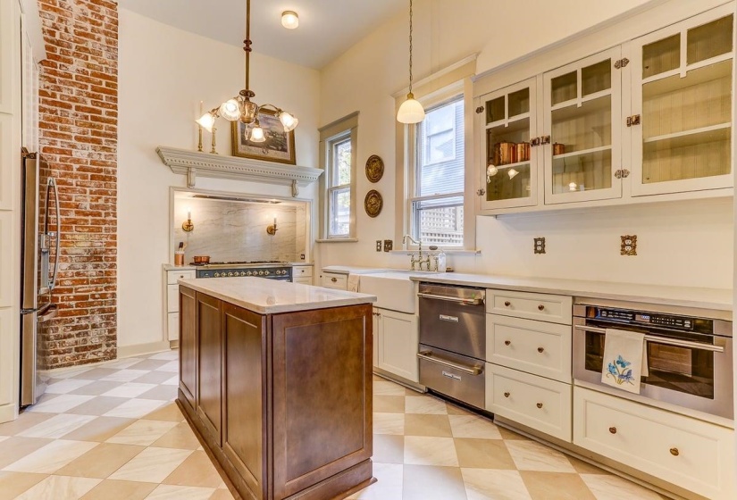 Kitchen featuring stainless steel appliances, pendant lighting, glass insert cabinets, light stone counters, and white cabinetry