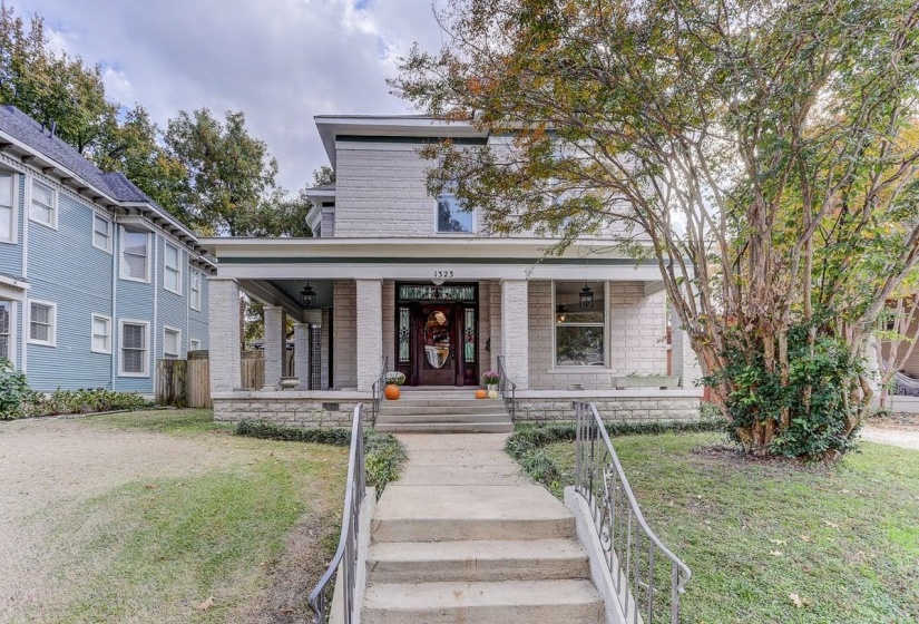 View of front of house with covered porch, a front yard, and stairs