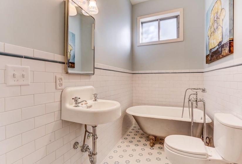 Full bath featuring a soaking tub, tile walls, wainscoting, and tile patterned floors