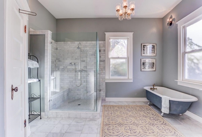 Full bath with a freestanding tub, a shower stall, a chandelier, and light tile patterned flooring