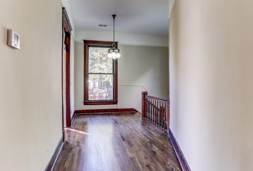 Spare room with dark wood-style floors and a chandelier