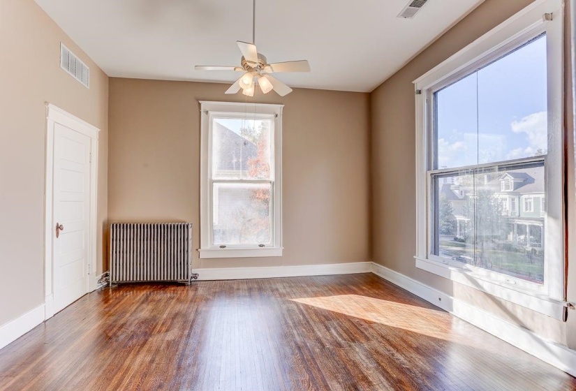 Empty room featuring radiator heating unit, wood finished floors, and ceiling fan