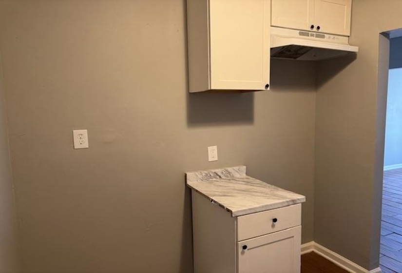 Interior space featuring baseboards, under cabinet range hood, white cabinets, and light countertops