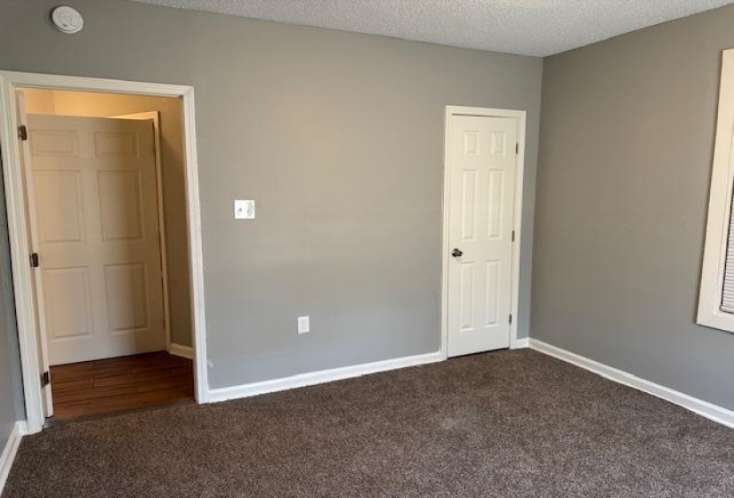 Unfurnished bedroom with dark carpet, baseboards, and a textured ceiling