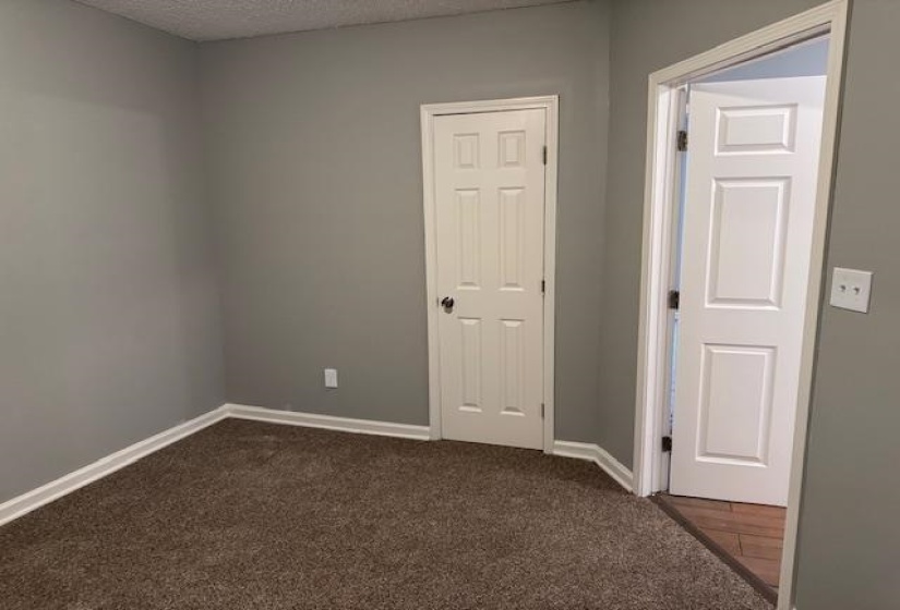 Empty room featuring baseboards, a textured ceiling, and dark carpet