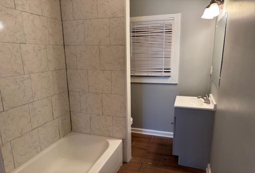 Full bath featuring baseboards, toilet, wood finished floors, and vanity