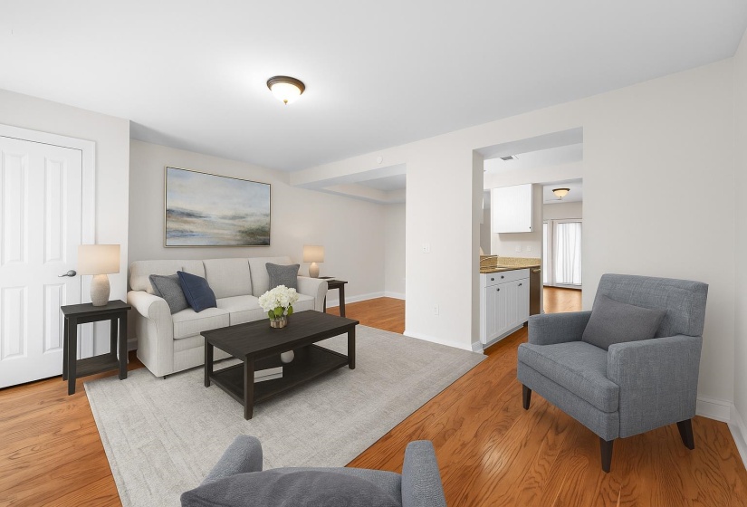 This spacious living room flows seamlessly into the kitchen and dining areas, showcasing gorgeous hardwoods and a clean, move-in-ready feel. Ideal for hosting or cozy nights in. This photo has been virtually staged.