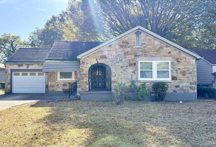 View of front of home featuring stone siding, concrete driveway, a garage, and a front yard