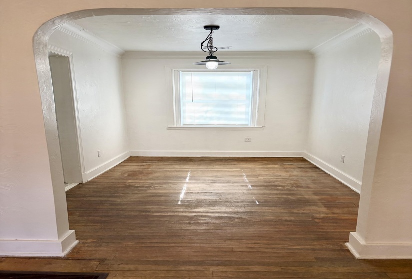 Unfurnished dining area with arched walkways, ornamental molding, and dark wood-style flooring