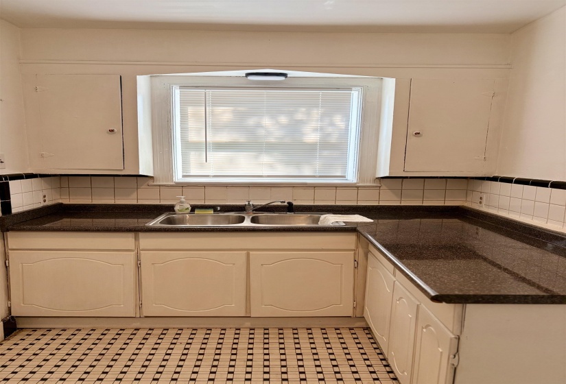 Kitchen featuring decorative backsplash, white cabinetry, and dark stone countertops