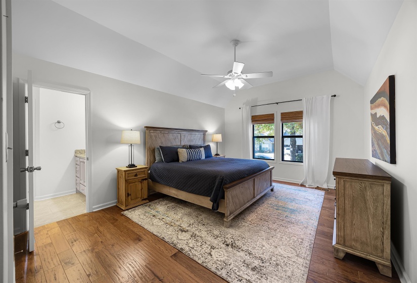 Bedroom with hardwood / wood-style floors, a ceiling fan, lofted ceiling, and ensuite bath