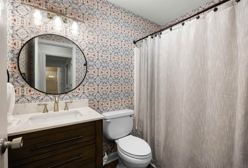 Bathroom with wallpapered walls, a shower with curtain, and vanity