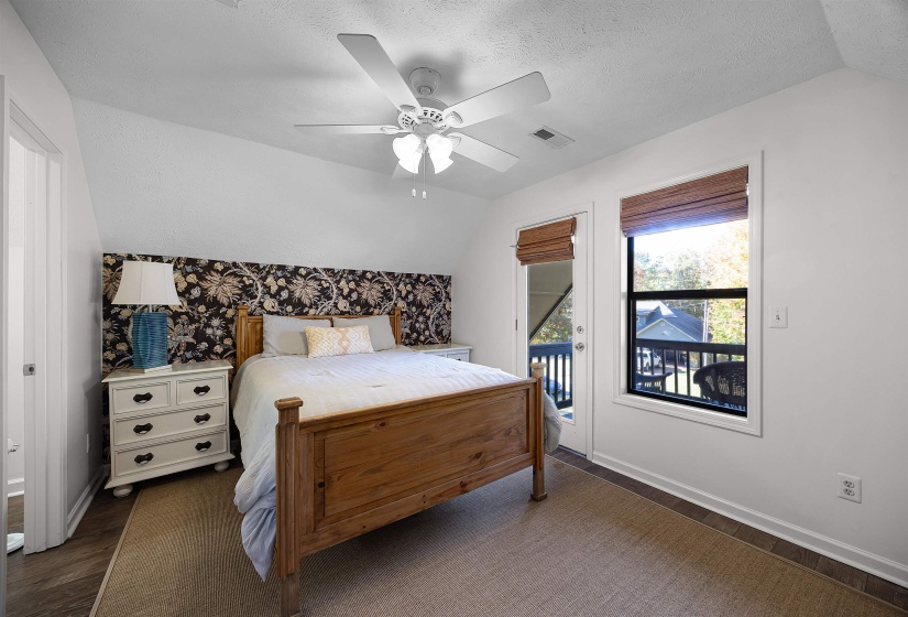Bedroom with vaulted ceiling, dark wood finished floors, access to outside, ceiling fan, and a textured ceiling
