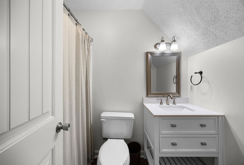Bathroom featuring a shower with shower curtain, a textured ceiling, vanity, and lofted ceiling