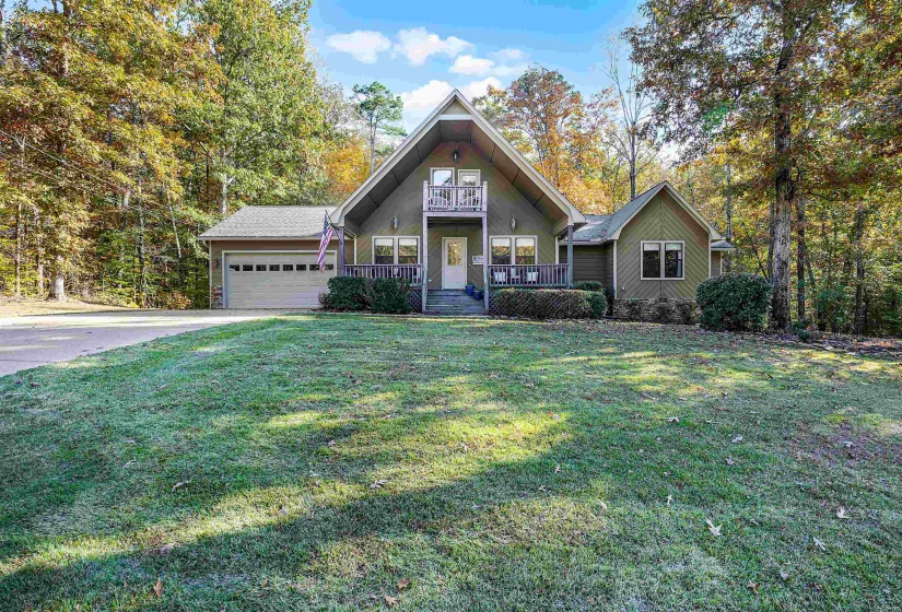 View of front of property featuring covered porch, an attached garage, driveway, and a front yard