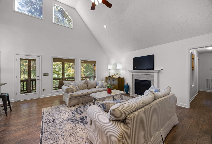 Living room featuring high vaulted ceiling, a fireplace, dark wood-style floors, a ceiling fan, and recessed lighting