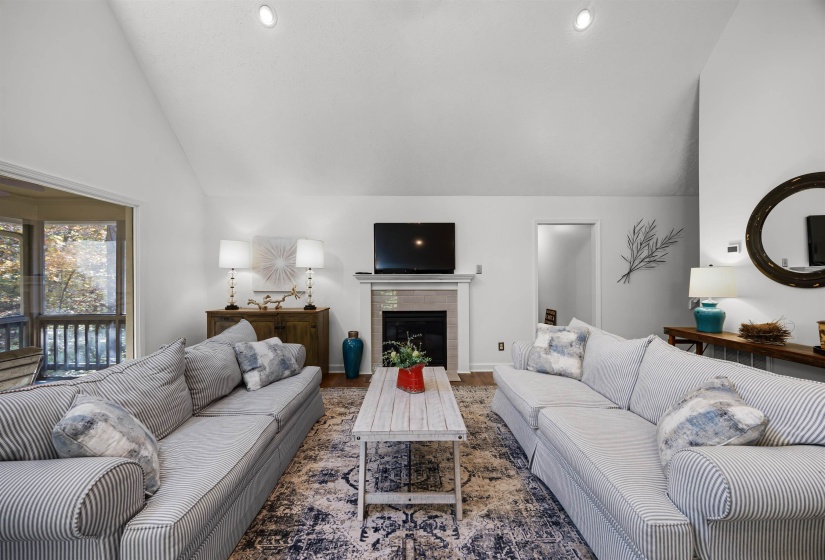 Living area with a fireplace, wood finished floors, recessed lighting, and high vaulted ceiling
