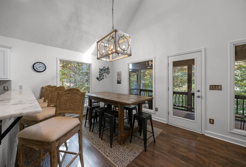 Dining space featuring dark wood-style flooring, high vaulted ceiling, a chandelier, and a textured ceiling
