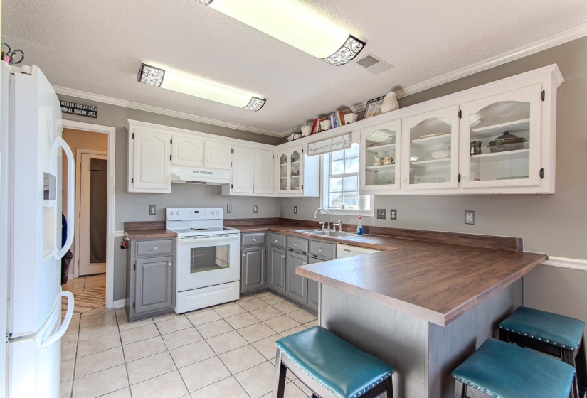 Kitchen featuring glass insert cabinets, gray cabinets, white appliances, ornamental molding, and white cabinets