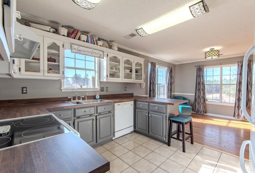Kitchen featuring glass insert cabinets, a peninsula, a breakfast bar, light tile patterned flooring, and gray cabinetry