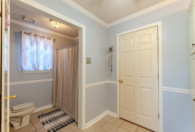 Full bath featuring a textured ceiling, light tile patterned floors, a shower with curtain, and crown molding