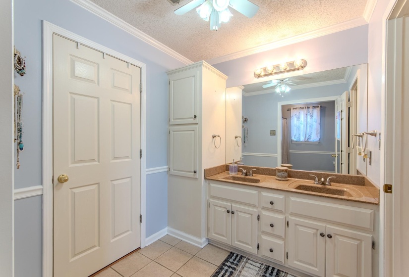 Bathroom featuring double vanity, light tile patterned flooring, a ceiling fan, a textured ceiling, and crown molding
