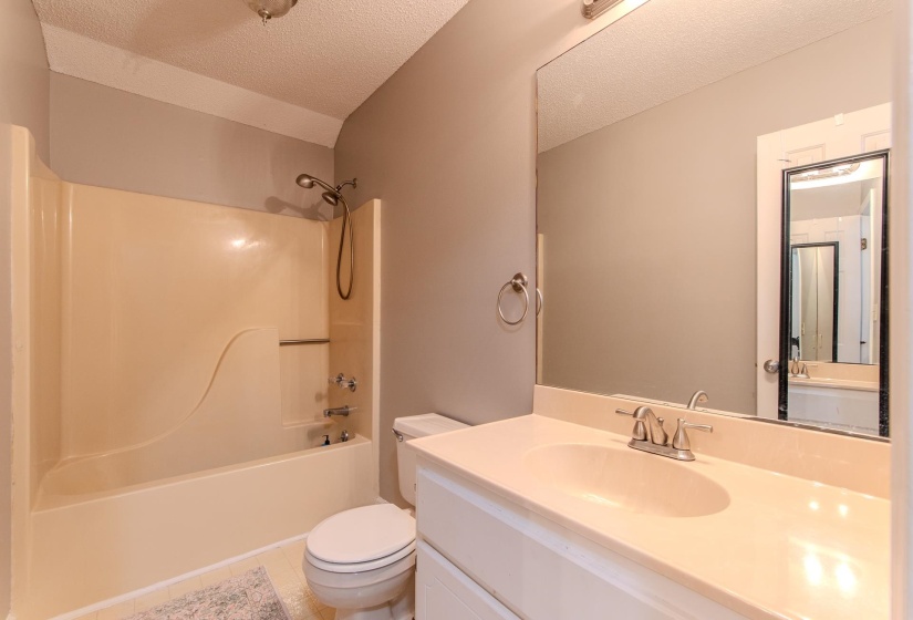 Bathroom featuring a textured ceiling, vanity, tub / shower combination, and light tile patterned floors