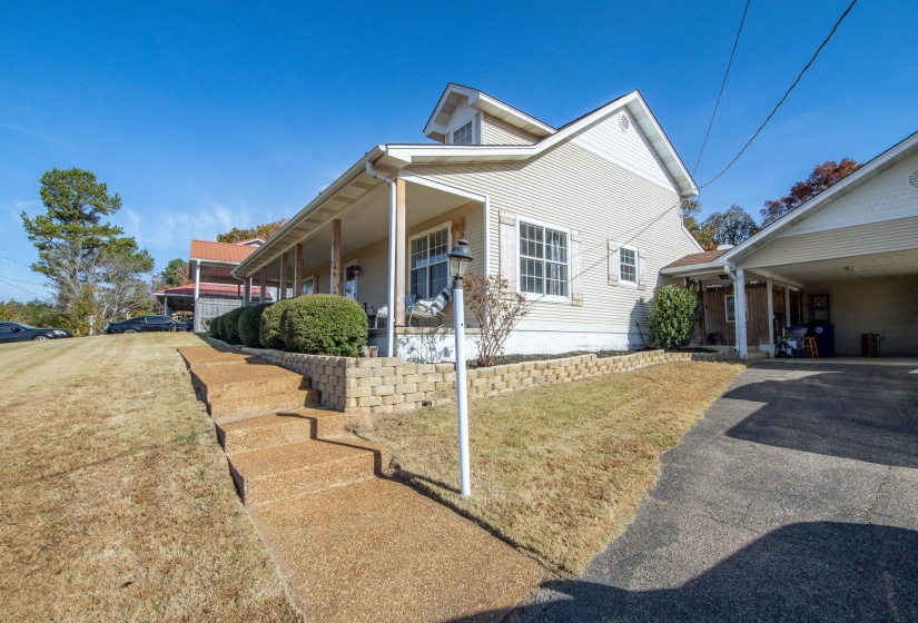 View of home's exterior featuring a lawn, covered porch, an attached carport, and asphalt driveway