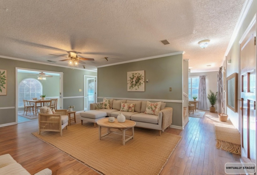 Living room with ornamental molding, wood-type flooring, a textured ceiling, and a ceiling fan