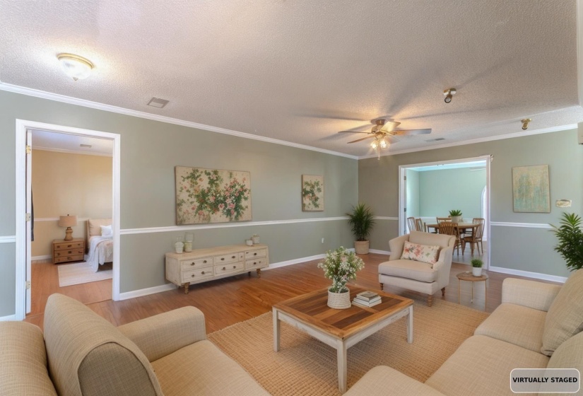 Living room featuring crown molding, a textured ceiling, wood finished floors, and a ceiling fan