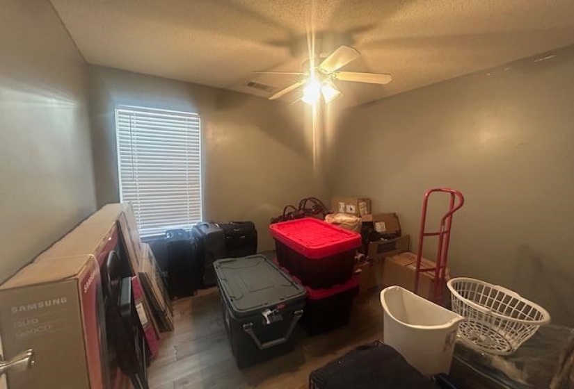 Bedroom featuring a textured ceiling, wood finished floors, and ceiling fan