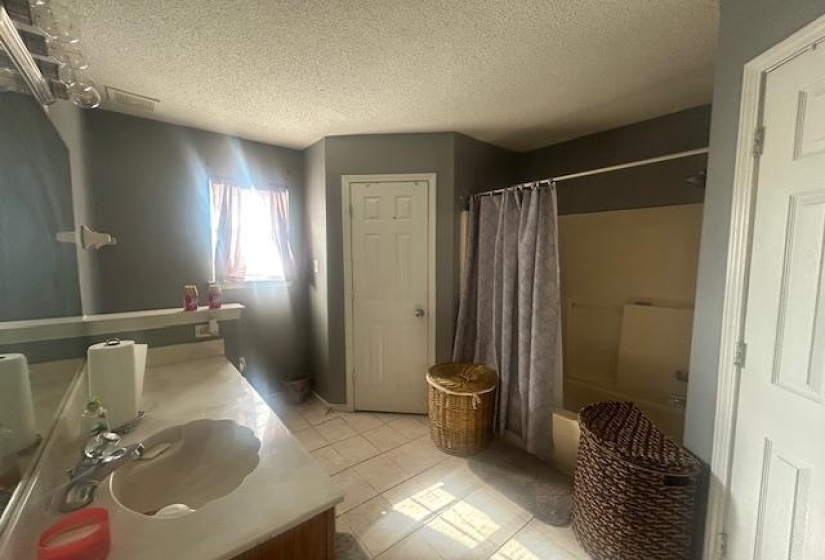 Full bath with a textured ceiling, vanity, shower / bathtub combination with curtain, and light tile patterned floors
