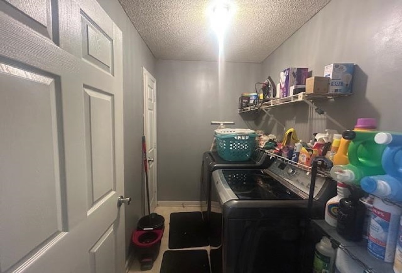 Laundry area featuring a textured ceiling and washer and clothes dryer