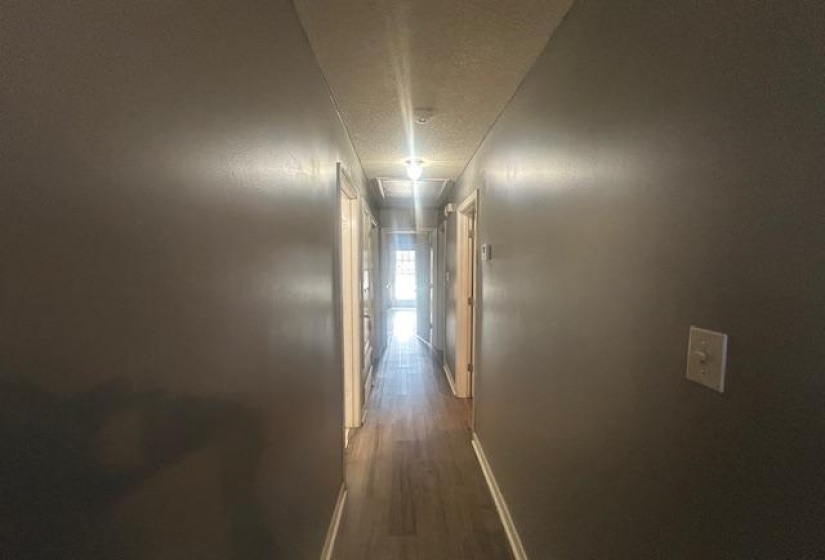 Hall with dark wood-style flooring, a textured ceiling, and attic access