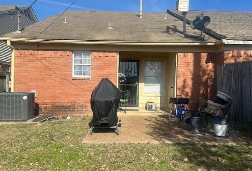 Back of property featuring roof with shingles, a patio area, a lawn, brick siding, and a chimney