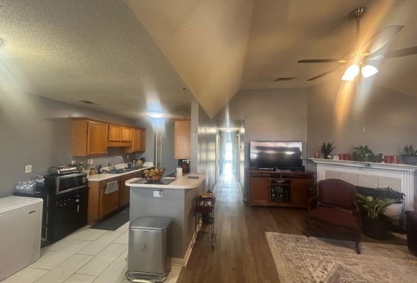 Kitchen with brown cabinetry, open floor plan, light countertops, ceiling fan, and light wood-style floors