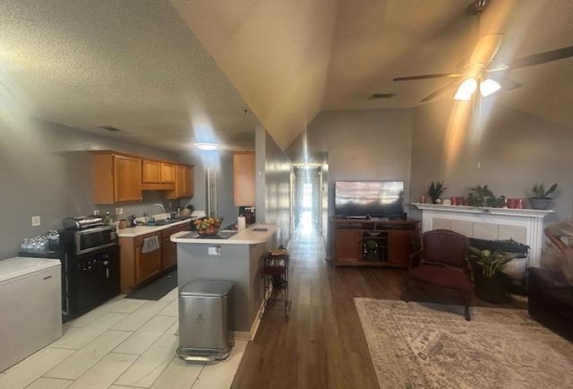 Kitchen with open floor plan, light countertops, brown cabinets, vaulted ceiling, and light wood-style flooring