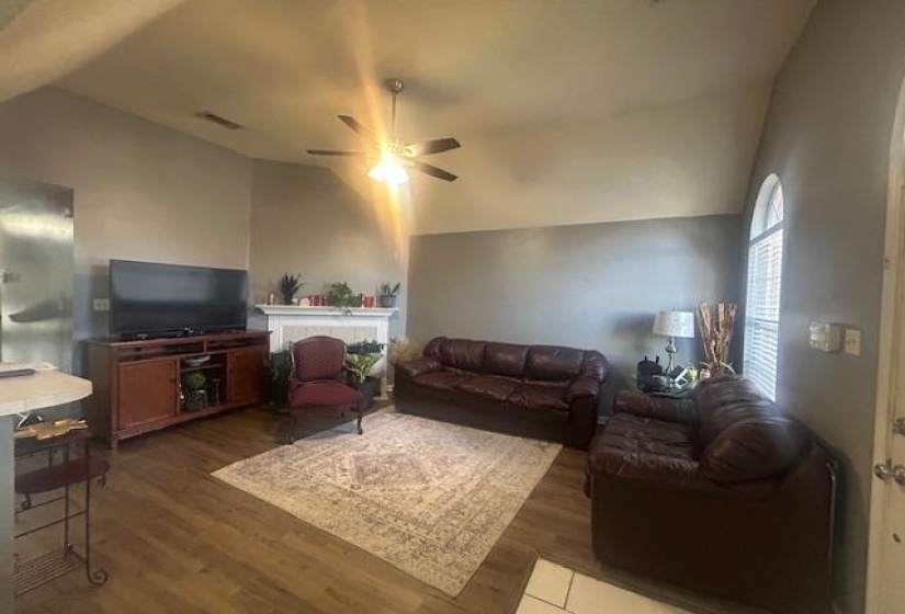 Living room with lofted ceiling, wood finished floors, and ceiling fan