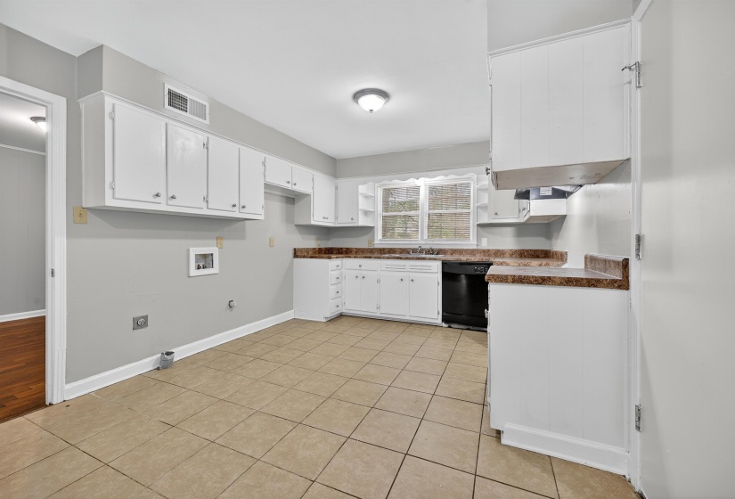 Kitchen with white cabinetry, black dishwasher, light tile patterned floors, and dark countertops