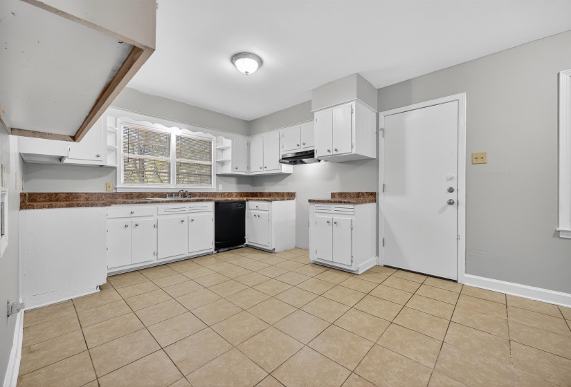 Kitchen featuring white cabinets, dark countertops, open shelves, black dishwasher, and light tile patterned flooring