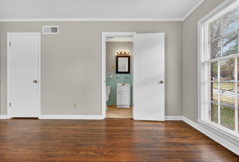 Unfurnished bedroom with ornamental molding, dark wood-style flooring, tile walls, and connected bathroom