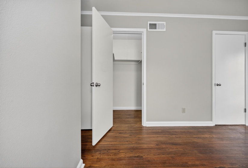 Unfurnished bedroom featuring dark wood-style flooring and a walk in closet