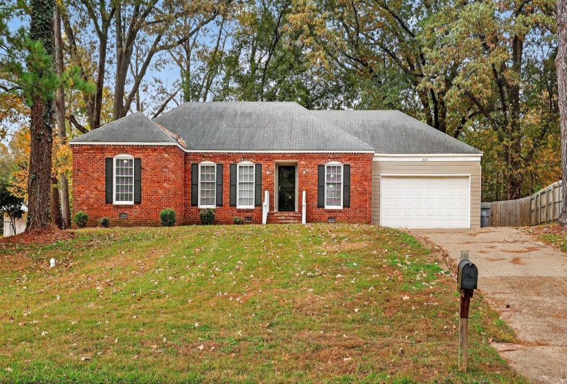 View of front of house featuring brick siding, driveway, and a garage