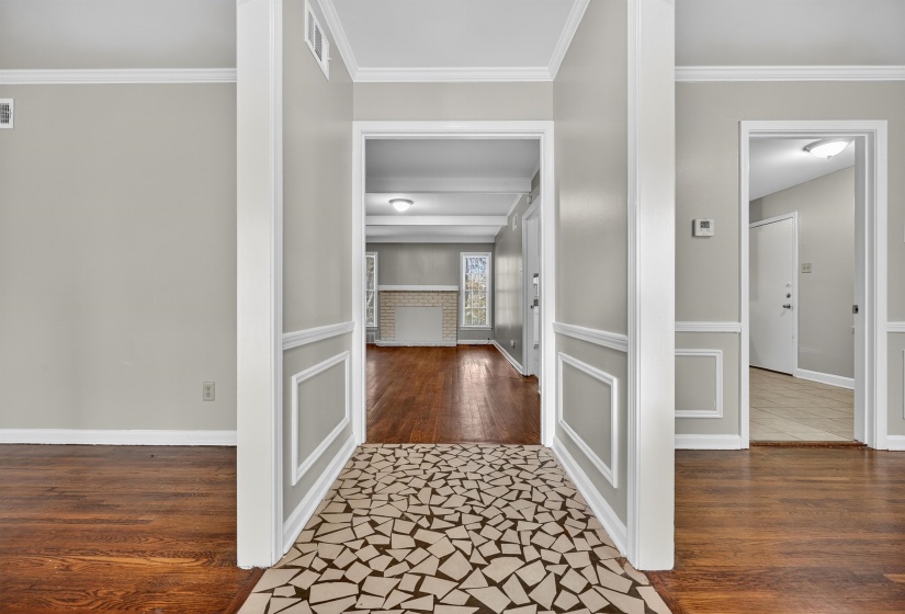 Hallway featuring crown molding, dark wood-style floors, wainscoting, and a decorative wall